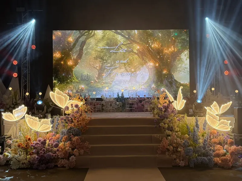 เวทีป่าเรืองแสงบนจอ ไฟสปอตไลต์ และโคมผีเสื้อสองข้างทางขึ้น